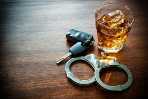 DUI concept with a glass of whiskey, car keys and handcuff.
