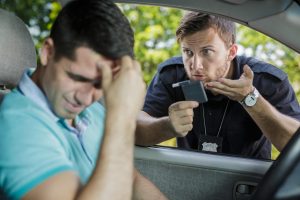 a cop checking a man for DUI with a Breathalyzer test